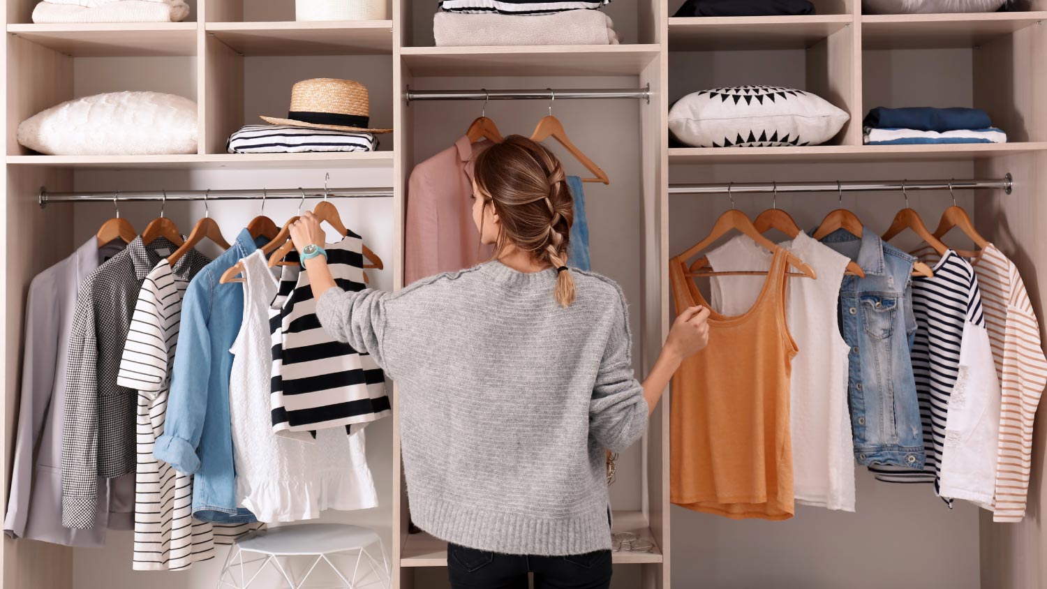 Woman choosing outfit from large wardrobe closet