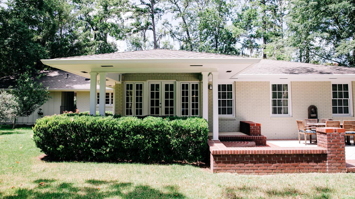 The exterior of a cream brick house with white vintage windows