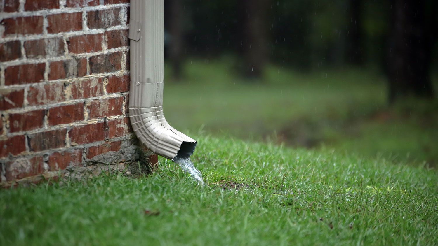 A gutter’s downspout working during the rain