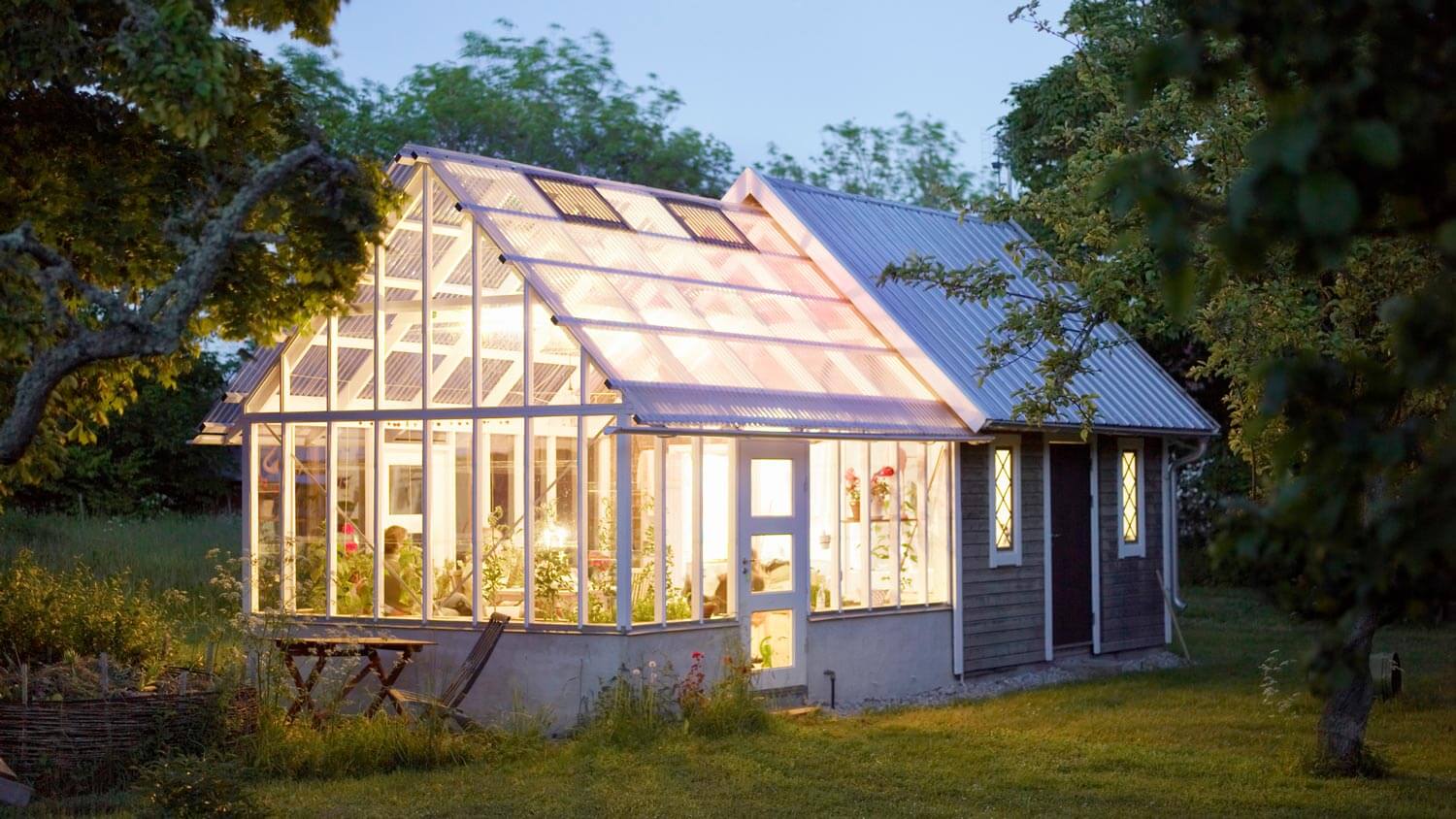 An illuminated glass greenhouse at dusk