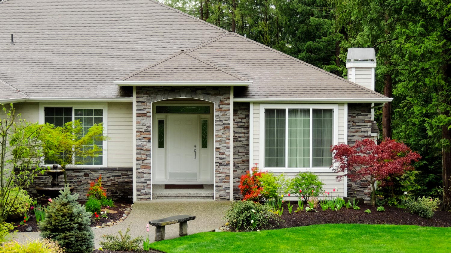 A modern home with green grass and trees in front yard