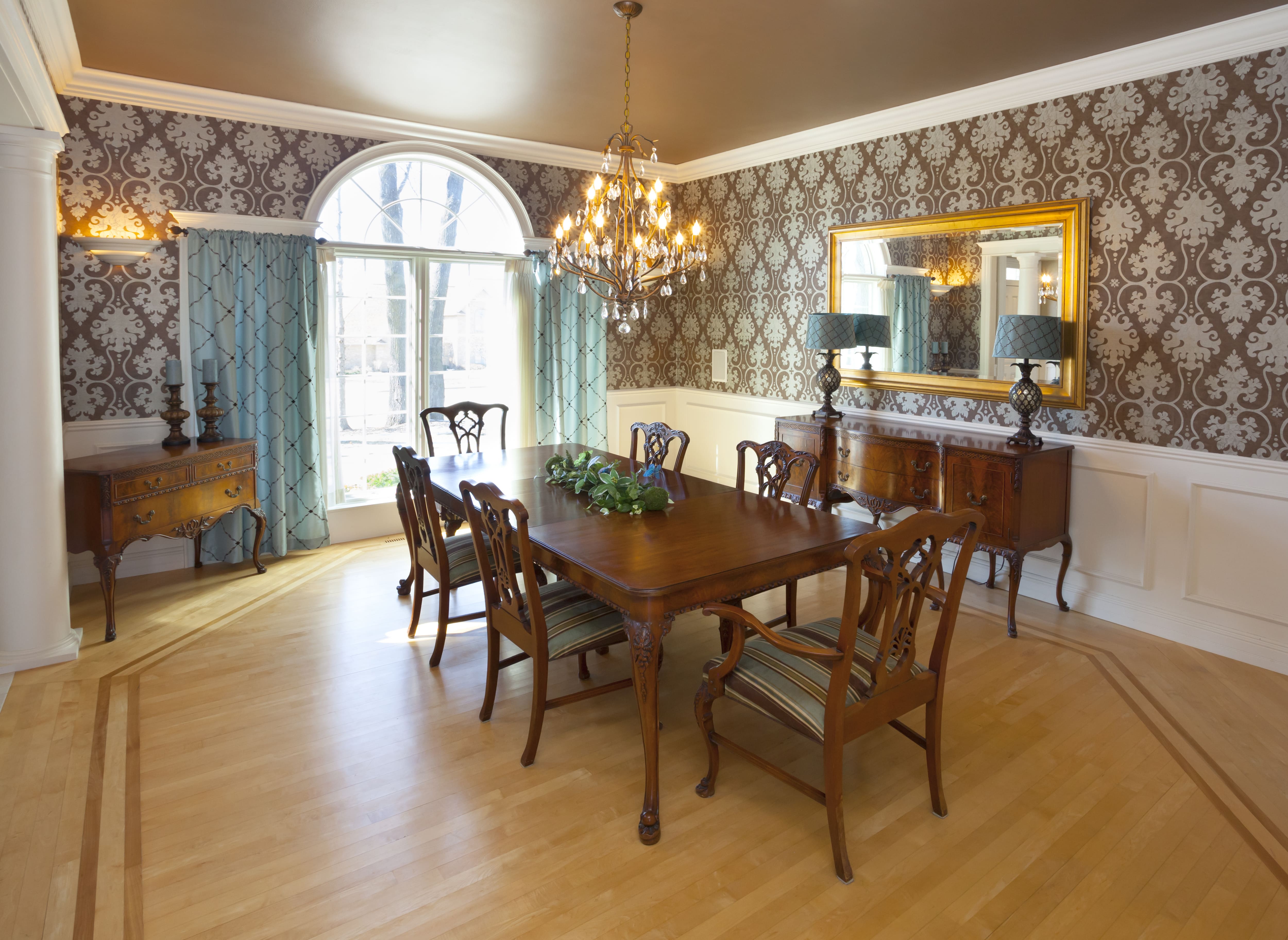 Grand dining room with walls lined with traditional white wainscoting paired with wallpaper