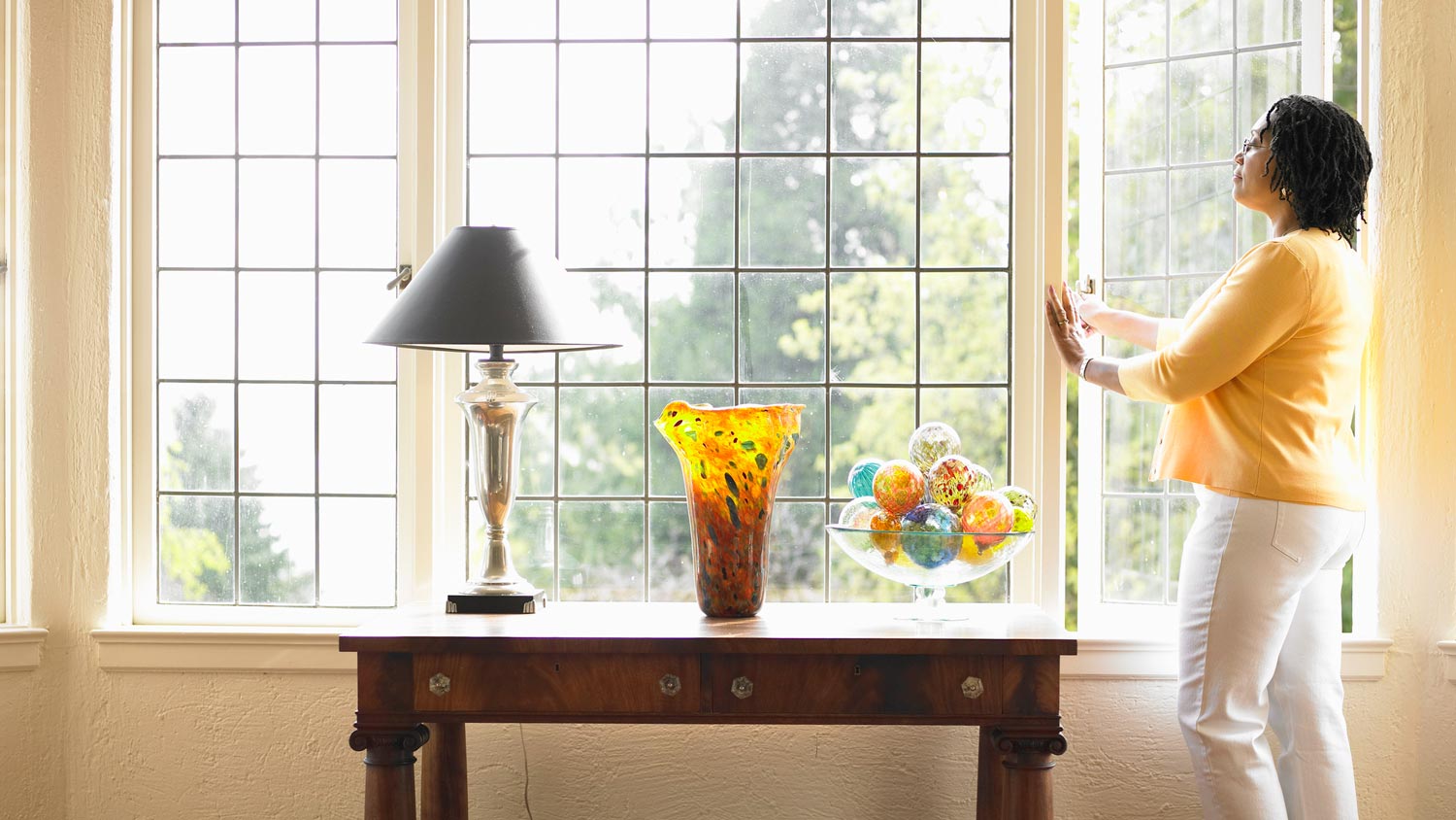 Woman opening window in living room 